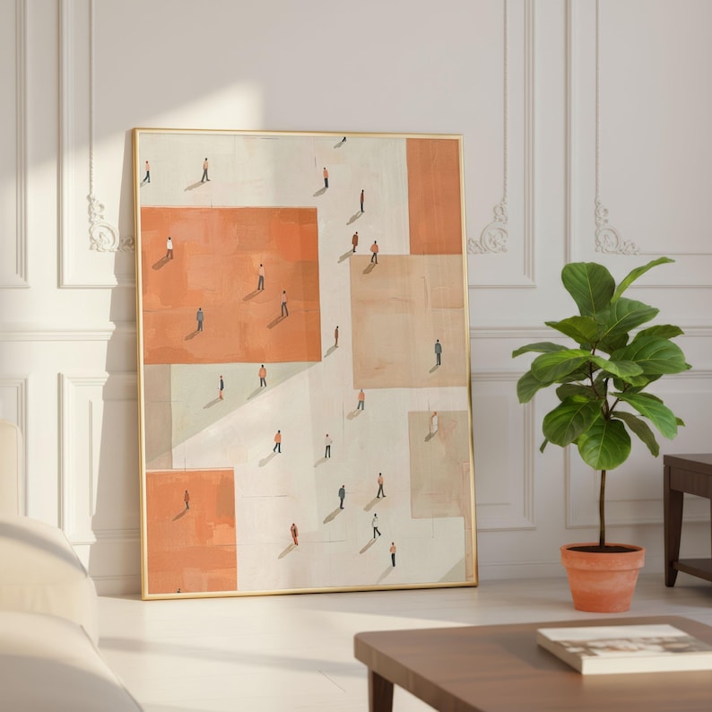 May include: An abstract art print featuring a gold frame. The artwork depicts a geometric design with orange and beige blocks, populated by tiny figures. The print is leaning against a white wall, with a potted plant and a coffee table in the foreground.