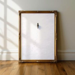 May include: An ornate gold framed print. The artwork depicts a cat walking across a white surface, leaving paw prints. The print is displayed on a wooden floor against a neutral wall, with shadows from a window.