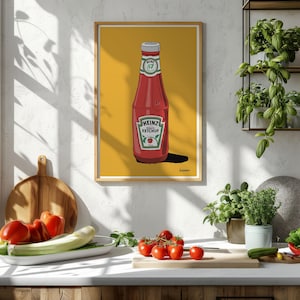 May include: A framed print featuring a stylized illustration of a Heinz ketchup bottle against a yellow background. The bottle is red with white and green labels, and the text "Heinz Tomato Ketchup" is visible. The artwork is in a kitchen setting.