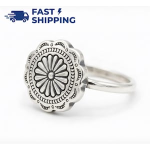Puede incluir: Un anillo de plata con un diseño detallado en forma de flor. El anillo presenta un patrón floral central rodeado de detalles intrincados. La banda es lisa y sencilla. La imagen también incluye el texto "FAST SHIPPING".