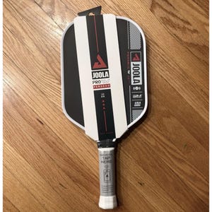 May include: A black and white pickleball paddle with the text "JOOLA PROV PERSEUS". The paddle has a white handle and a black and white striped design. The paddle is made in the USA.