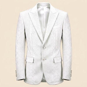 May include: A white blazer featuring a textured snakeskin pattern throughout the fabric. This garment includes a notched lapel, two front buttons, two flap pockets, and four small buttons on each sleeve cuff, all lined with a smooth white fabric.