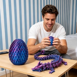 May include: A selection of dragon-themed ornaments. Features a large, iridescent blue and purple dragon egg, a small dragon egg, and a segmented dragon figurine. The items are displayed on a wooden table.
