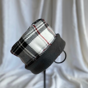 May include: A black, white, and red plaid fleece hat with a gray fleece lining.