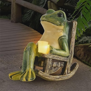 May include: A whimsical frog statue in a rocking chair, holding a glowing cube. The frog is green and yellow, with a relaxed expression. The chair has a rustic, wooden appearance, perfect for garden decor.