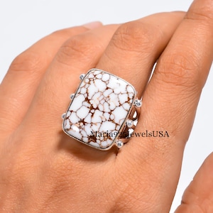 May include: A rectangular ring featuring a white stone with brown matrix patterns set in a silver band. The stone has a smooth, polished surface with intricate veining. The text Maria925JewelsUSA is visible across the center of the stone.