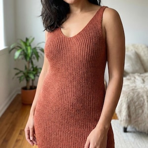Puede incluir: Vestido de punto sin mangas, color óxido, con cuello en V. El vestido tiene una textura acanalada y una silueta ajustada. El vestido llega a la rodilla y parece estar hecho de un material suave y cómodo. El vestido es adecuado para ropa casual.