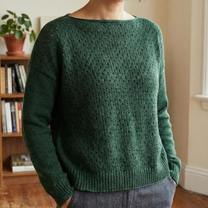 Puede incluir: Un suéter de punto verde oscuro con cuello barco y mangas largas. El suéter tiene un diseño de punto abierto y texturizado en todo el cuerpo y las mangas. El dobladillo inferior y los puños son acanalados. El suéter está hecho de un material suave y cómodo.