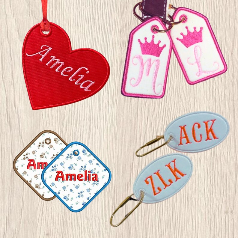 May include: A collection of embroidered fabric tags including a red heart-shaped tag with the name Amelia, two white rectangular tags with pink crowns and letters M and L, two floral square tags with the name Amelia, and two oval light blue tags with orange letters.