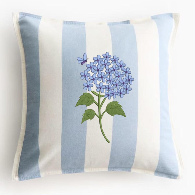 May include: Square throw pillow with a blue and white striped pattern. The pillow features a floral design of blue hydrangea flowers and a butterfly. The pillow has a white border.