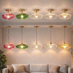 Puede incluir: Una colección de lámparas colgantes con diseño floral. Las lámparas presentan pantallas de vidrio en varios colores, incluyendo rojo, verde, transparente y amarillo. Cada lámpara tiene un accesorio dorado y un cable colgante.