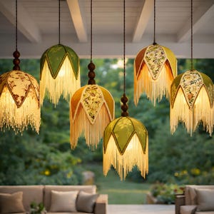 May include: Six pendant lamps with floral patterned shades in shades of yellow, green, and brown. Each lamp has a fringe trim and a dark brown wooden accent. The lamps are suspended from a white ceiling.