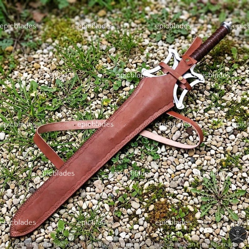 May include: A sword with a brown leather scabbard and a brown leather-wrapped handle. The sword features a silver-colored metal crossguard with an intricate, open-work design. A brown leather strap is attached to the scabbard for carrying purposes.