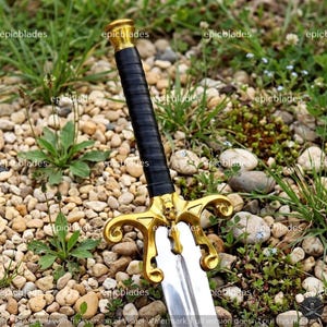 May include: A sword featuring a black wrapped handle, a gold-colored crossguard with a skull detail, and a metallic blade. The word epicblades is repeated across the image as a watermark. The sword is positioned vertically with the hilt at the top.