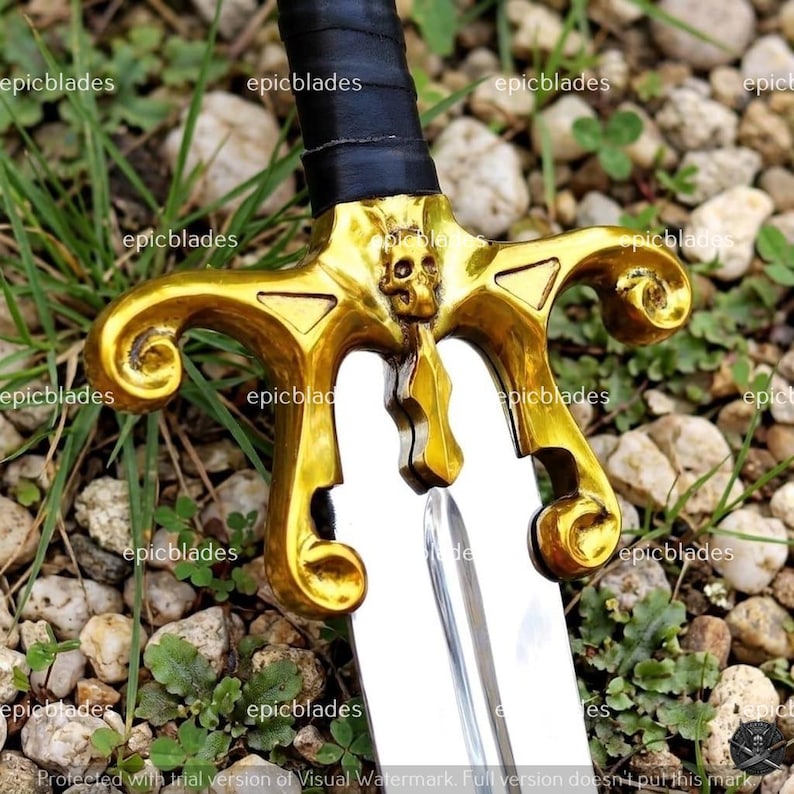 May include: A sword featuring a polished silver blade and a gold-colored metal crossguard with a central skull emblem. The handle is wrapped in black material. The text "epicblades" is repeated across the image as a watermark.
