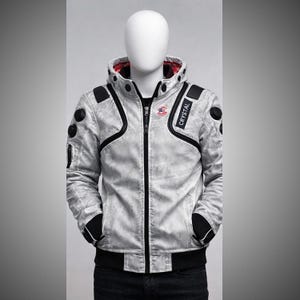 May include: A light grey jacket with black detailing and the word "CRYSTAL" on the sleeve. The jacket features a zip-up front, a hooded collar, and black patches on the shoulders and sleeves. The jacket is displayed on a mannequin.