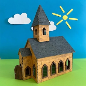 Puede incluir: Una maqueta artesanal de una iglesia hecha de cartón, con un exterior de color beige que imita la piedra, un tejado de tejas gris oscuro y un alto campanario. La iglesia tiene ventanas arqueadas y una puerta de madera. El fondo incluye nubes y un sol de papel.