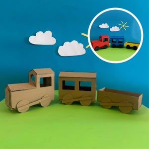 May include: A cardboard train set with three cars, including an engine and two boxcars. The train is made of brown cardboard with circular wheels. A smaller, colorful train set is in a circular inset, with red, blue, and yellow cars.
