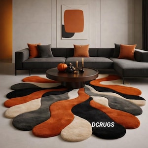 Pode incluir: Um tapete abstrato com um design ondulado e orgânico em tons de laranja, preto, cinza e creme. O tapete está colocado em frente a um sofá cinza escuro e uma mesa de centro redonda, criando um ambiente moderno e acolhedor.