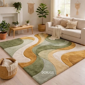 May include: A large, rectangular area rug with a wavy, abstract design in shades of green, gold, and cream. The rug is placed in a living room setting, with a sofa, plants, and a woven basket visible. The text "DCRUGS" is visible on the rug.