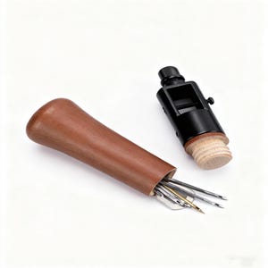 May include: A brown wooden awl handle with a set of needles and a black metal tool with a wooden cork. The needles are various sizes and shapes. The tools are on a white background.