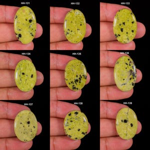 Peut inclure: Une collection de neuf pierres précieuses ovales polies, de couleur jaune-vert avec des inclusions noires tachetées, étiquetées de HH-131 à HH-139. Chaque pierre présente un motif unique de taches sombres et de veines sur un fond chartreuse.