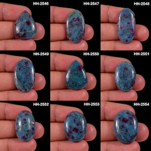 May include: A collection of nine polished cabochon gemstones, each featuring a blue base with embedded red inclusions. The stones are labeled HH-2546 through HH-2554, displaying various oval and teardrop shapes with smooth, reflective surfaces.