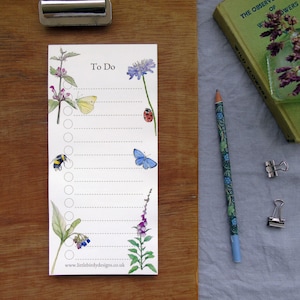 May include: A white to-do list notepad with a floral design. The notepad features a blue butterfly, a yellow butterfly, a bumblebee, a ladybug, and a variety of flowers. The text "To Do" is printed at the top of the notepad. The website address "www.littlebirdydesigns.co.uk" is printed at the bottom of the notepad.