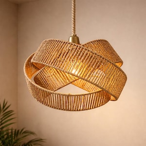 May include: A woven rope pendant light. The light fitting is made of natural-coloured rope, with a circular design. The light hangs from a matching rope and a brass-coloured metal fixture. The light bulb is visible inside the fixture.