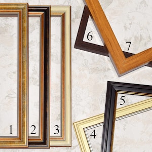 May include: A collection of picture frames in various styles and colors. The frames include gold, black, brown, and cream-colored options. Some frames are rectangular, while others are angled. The frames have decorative edges and are displayed against a patterned background.
