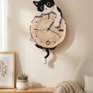 Peut inclure: Une horloge murale fantaisiste avec un chat noir et blanc sur un cadran en forme de rondin de bois. L'horloge a des aiguilles et des marqueurs noirs. La queue du chat pend. Un ajout charmant à la décoration intérieure.
