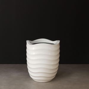 Pode incluir: Vaso de cerâmica branco com um design ondulado e texturizado. O vaso tem uma borda curva e um corpo cilíndrico. O interior escuro contrasta com o exterior branco brilhante. Mede aproximadamente 30 cm de altura, adequado para uso interno ou externo.