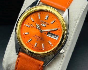 Vintage Seiko 5 Sports automatisk herrarmbandsur med dag- och datumfunktion, orange urtavla, självlysande