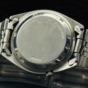 May include: Close-up of a stainless steel Seiko watch. The watch back features the text "WATER RESISTANT JAPAN 4 STAINLESS STEEL 362869 7009-3131R". The watch band is a silver-toned metal.