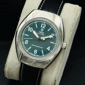 May include: A vintage Tudor Oyster watch with a silver case and a dark green dial. The watch features white hands and hour markers, a black leather strap with white stitching, and the text "SHOCK RESISTING".