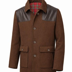 May include: A brown wool jacket with leather shoulder patches and a plaid lining. The jacket has two front pockets and a button-up closure. The collar is a classic style, and the overall design is a rugged, outdoorsy look.