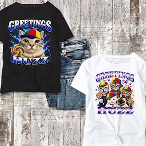 May include: A black t-shirt featuring a cat in a colorful propeller hat holding a lollipop with blue lightning graphics and the text GREETINGS HUZZ, and a white t-shirt featuring four cats in propeller hats with the text GREETINGS HUZZ.