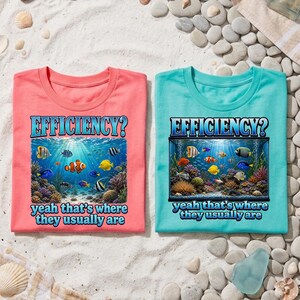 May include: Two short-sleeve t-shirts, one coral and one teal, each featuring a graphic print of a coral reef with various tropical fish. The text EFFICIENCY? yeah that's where they usually are is printed in blue above and below the image.