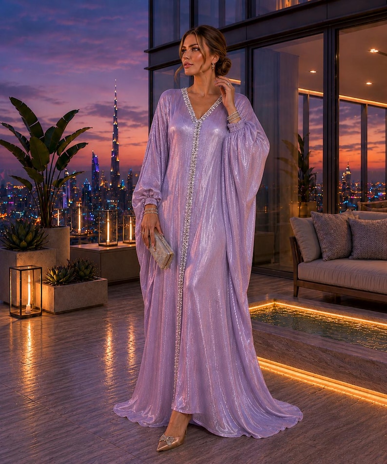 Puede incluir: Un vestido largo y fluido de color lavanda con escote en V y adornos. El vestido tiene mangas anchas y un dobladillo hasta el suelo. Se sostiene un peque&ntilde;o bolso de mano plateado. El fondo presenta un horizonte de la ciudad al anochecer.