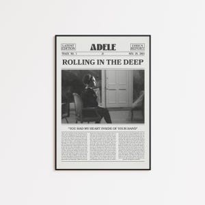 May include: Black framed poster featuring Adele's "Rolling in the Deep." The poster has a newspaper-like design with the song title, lyrics, and a black and white photo of Adele sitting in a chair. The text includes "Latest Edition" and "Lyrics Report."