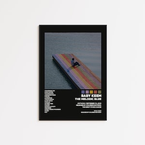May include: A framed poster featuring the album art for "The Melodic Blue" by Baby Keem. The image shows a person sitting on a colorful pier extending into a body of water. The poster includes the album title, tracklist, and release information.