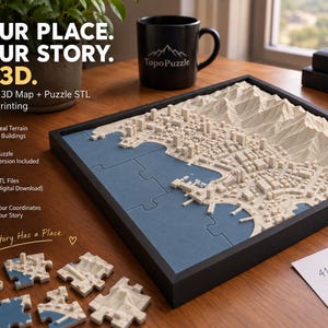 Könnte beinhalten: Ein quadratisches 3D-Topografie-Kartenpuzzle in einem schwarzen Rahmen, das eine Küstenstadt mit cremefarbenen Gebäuden und Bergen auf einer blauen Wasserbasis zeigt. Lose Puzzleteile liegen daneben, mit dem Text: YOUR PLACE. YOUR STORY. IN 3D.