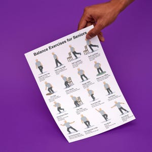 May include: A white poster titled "Balance Exercises for Seniors" held against a purple background. The poster features illustrations of various balance exercises, including standing on one leg, heel raises, and marching in place.