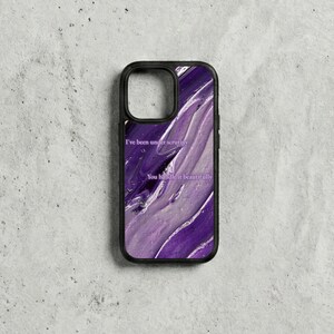 May include: Black phone case with a purple and white abstract design. The case features the text "I've been under scrutiny" and "You handle it beautifully" in a white font. The case has a black border.