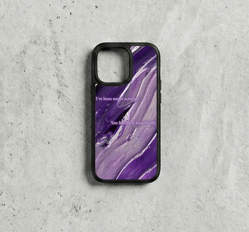May include: Black phone case with a purple and white abstract design. The case features the text "I've been under scrutiny" and "You handle it beautifully" in a white font. The case has a black border.