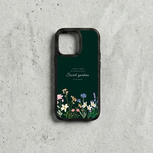 May include: A dark green phone case with a black border. The case features the text "I hate it here so I would go to Secret gardens in my mind" with a floral design at the bottom. The flowers include pink, yellow, white, and blue.