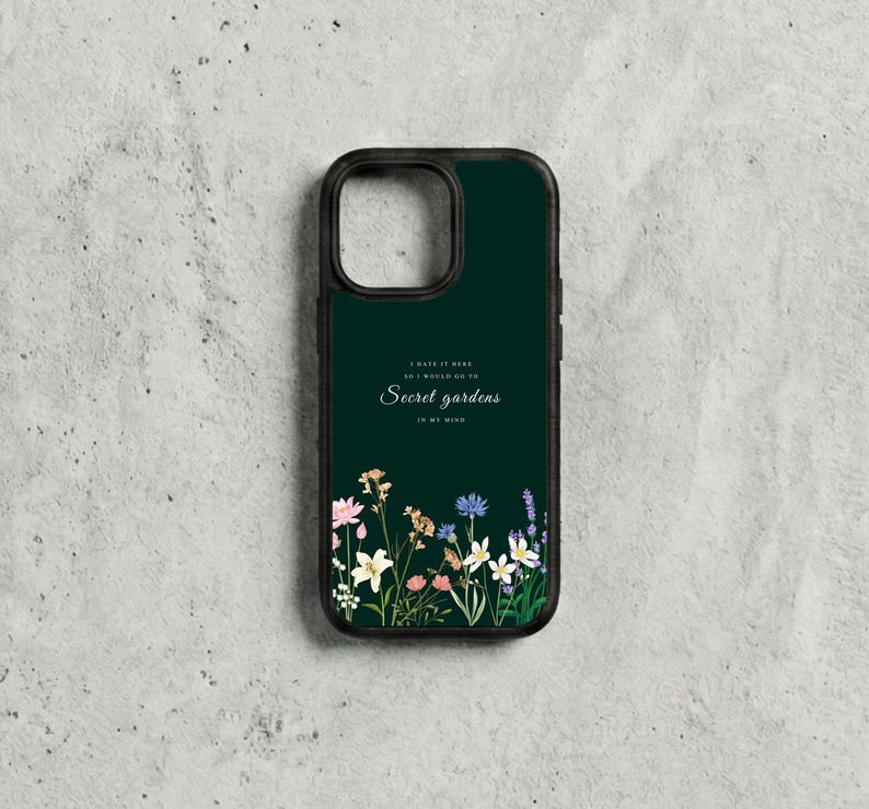 May include: A dark green phone case with a black border. The case features the text "I hate it here so I would go to Secret gardens in my mind" with a floral design at the bottom. The flowers include pink, yellow, white, and blue.