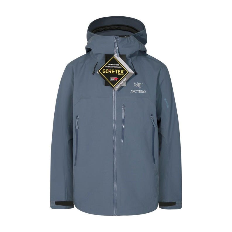 May include: A slate blue Arc'teryx jacket with a hood and a full-length zipper. The jacket features the Gore-Tex logo and the Arc'teryx logo. It has two zippered pockets on the front and a small logo on the sleeve.