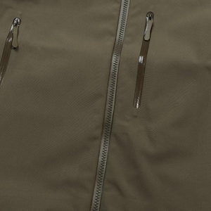 May include: Close-up of a khaki-colored jacket with three zippered pockets and a central zipper. The jacket's fabric has a subtle texture, and the zippers have silver pulls.