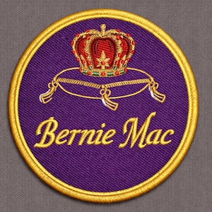 May include: Embroidered patch featuring a purple background with a gold border. The patch displays a red and gold crown above the name "Bernie Mac" in gold script. The crown sits atop a gold pillow.